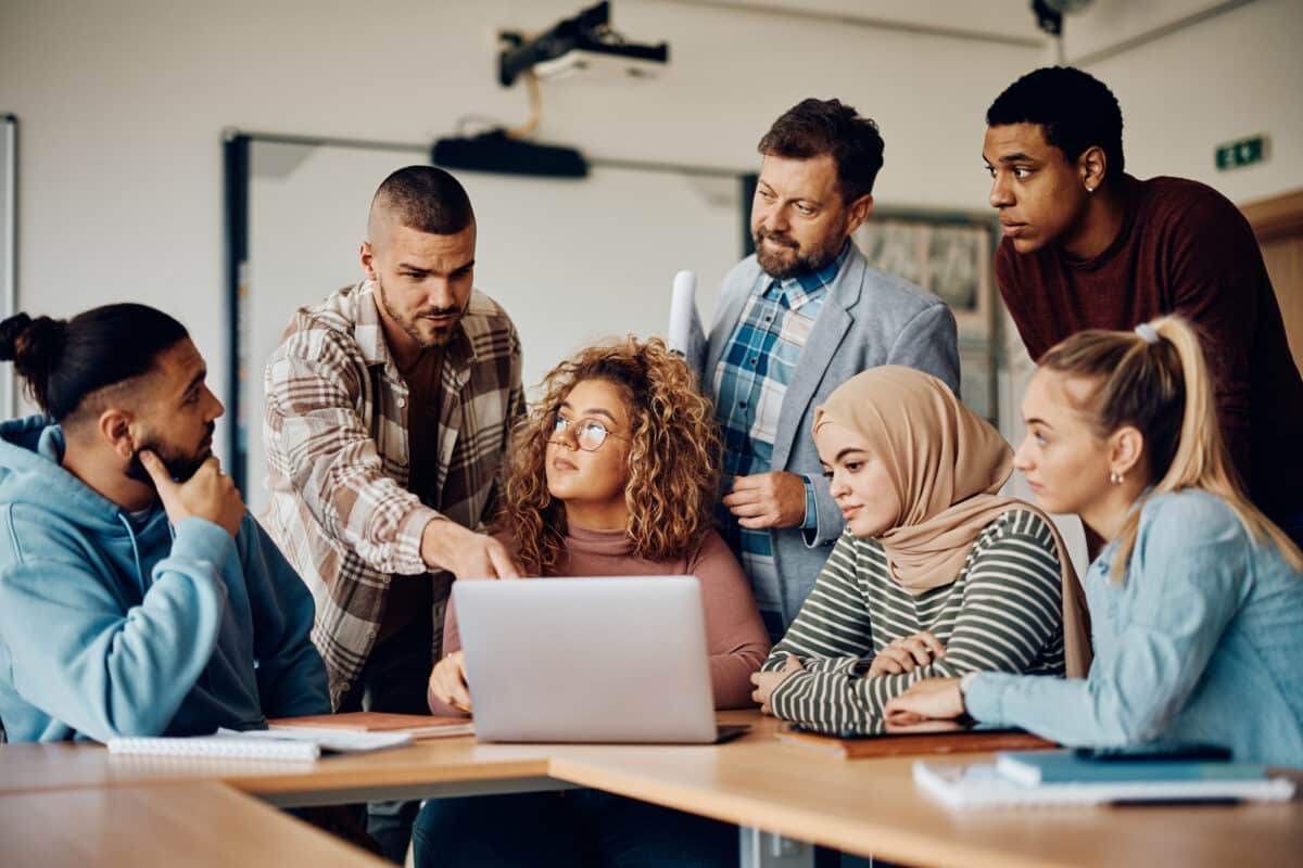 Een groep jonge werknemers die zich achter een laptop verzamelen op kantoor